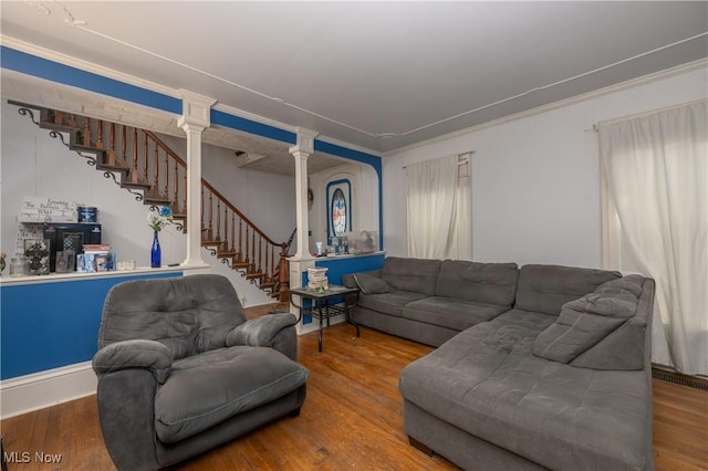 living room featuring wood finished floors, visible vents, stairway, ornate columns, and crown molding