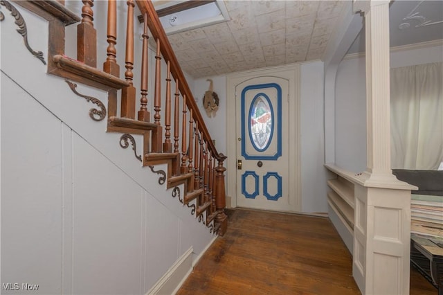 foyer entrance with dark wood-style floors, decorative columns, stairs, and a decorative wall