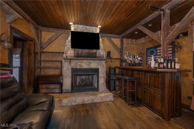 unfurnished living room featuring wooden ceiling, a stone fireplace, a dry bar, and hardwood / wood-style flooring