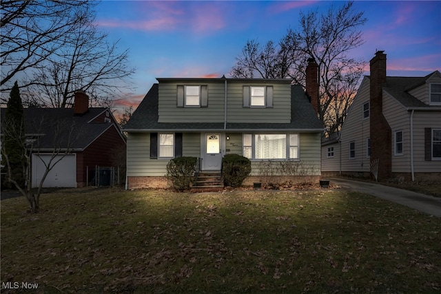 view of front of property with a shingled roof and a lawn