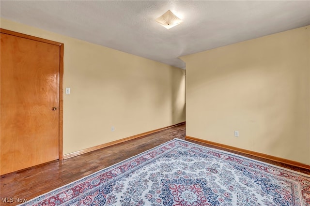 empty room featuring a textured ceiling, baseboards, and wood finished floors