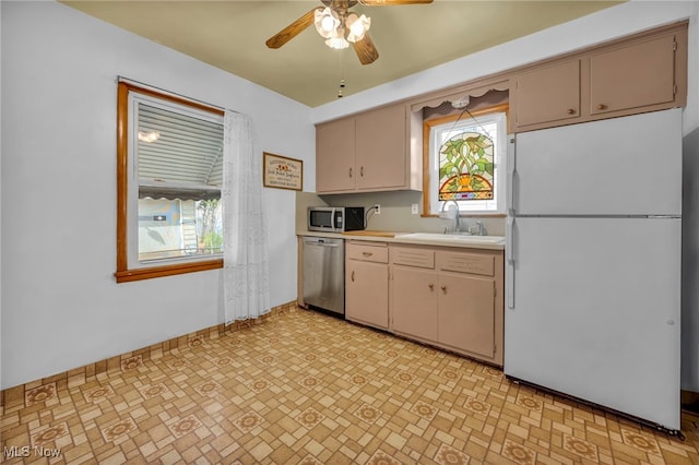 kitchen with a sink, a healthy amount of sunlight, baseboards, light countertops, and appliances with stainless steel finishes