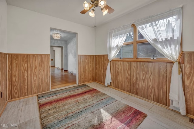 additional living space with a wainscoted wall, visible vents, wood walls, and a ceiling fan