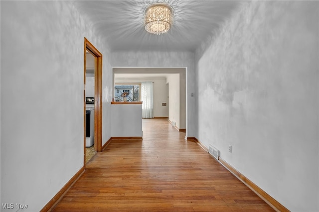 hall with baseboards, visible vents, and wood finished floors