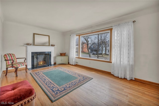 living room featuring hardwood / wood-style floors, a fireplace with flush hearth, and baseboards