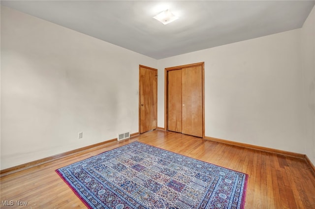 bedroom featuring visible vents, light wood-style flooring, and baseboards