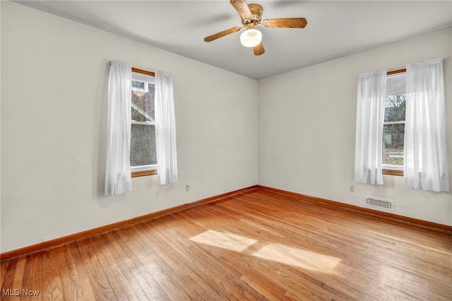 unfurnished room featuring light wood-style floors, plenty of natural light, visible vents, and baseboards