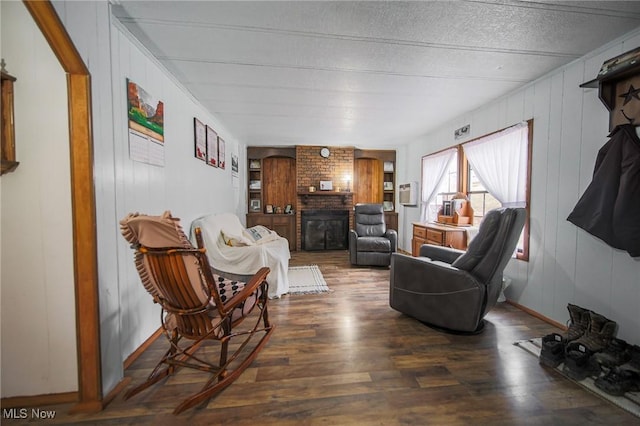 living room with a brick fireplace, baseboards, and wood finished floors