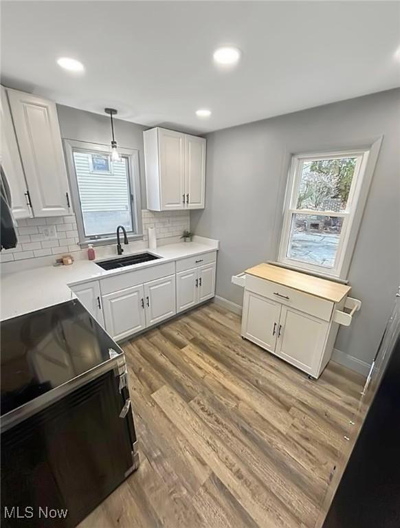 kitchen featuring light wood finished floors, white cabinetry, a wealth of natural light, and a sink