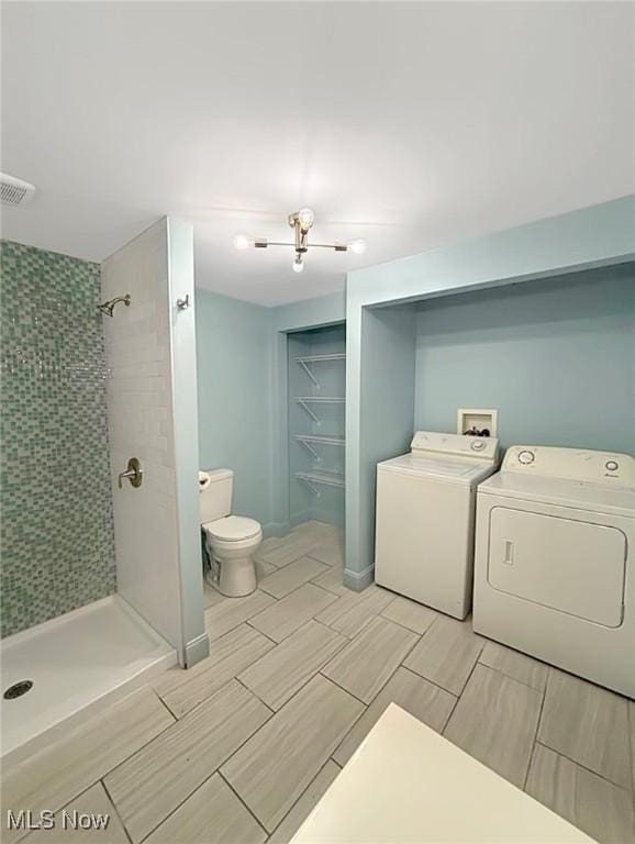 bathroom featuring visible vents, a shower stall, toilet, and separate washer and dryer