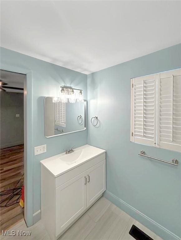 bathroom with wood finished floors, vanity, and baseboards