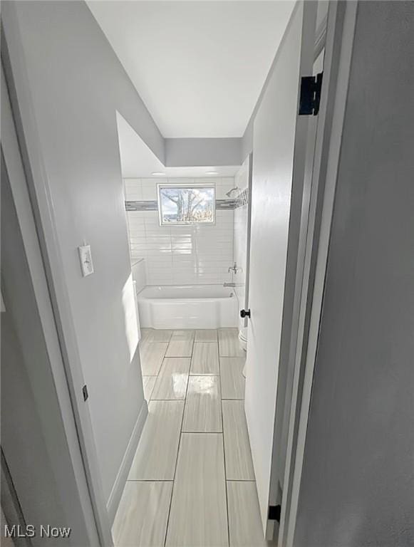 bathroom featuring toilet, bathtub / shower combination, and baseboards