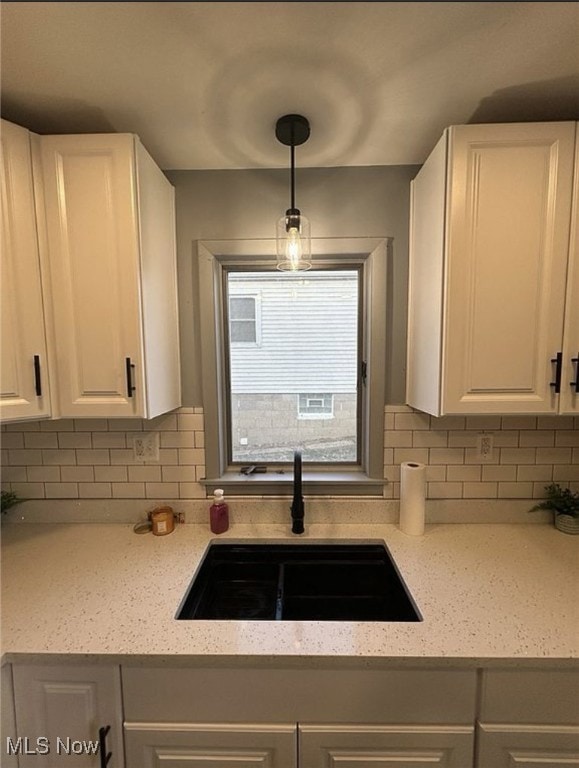 kitchen featuring decorative light fixtures, a sink, white cabinetry, and decorative backsplash