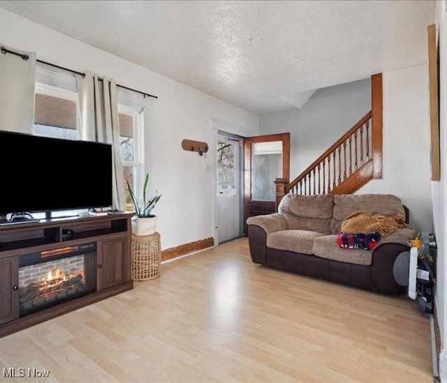 living room with light wood-style floors, stairs, baseboards, and a textured ceiling