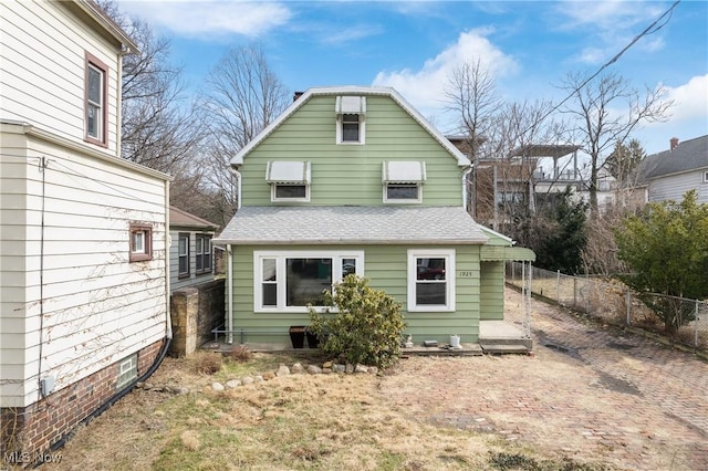 back of property featuring a shingled roof, fence, and a gambrel roof