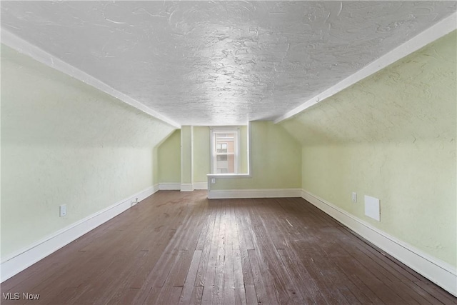 bonus room featuring wood-type flooring, vaulted ceiling, a textured ceiling, and baseboards