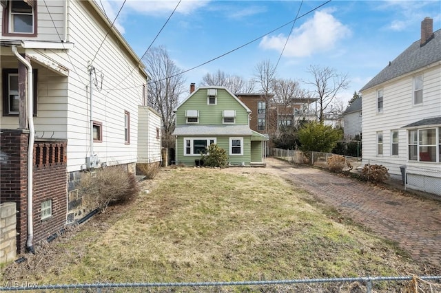 rear view of property with a lawn and fence