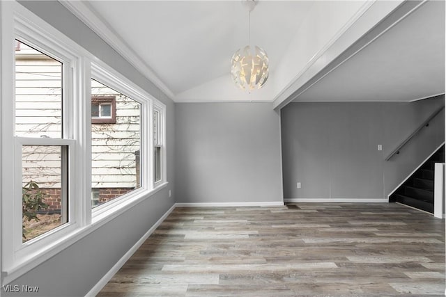 spare room with a notable chandelier, lofted ceiling, wood finished floors, baseboards, and stairs