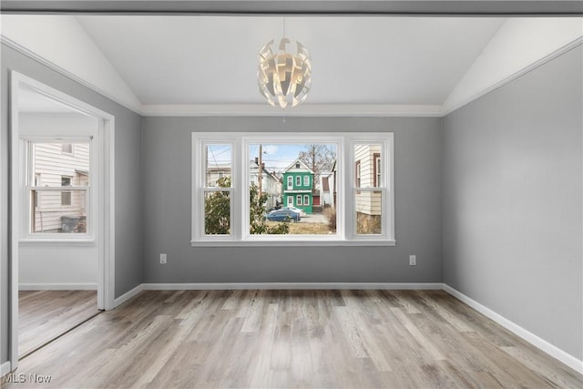 unfurnished dining area with lofted ceiling, light wood finished floors, baseboards, and an inviting chandelier