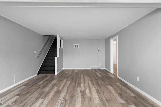 unfurnished living room featuring visible vents, stairway, baseboards, and wood finished floors