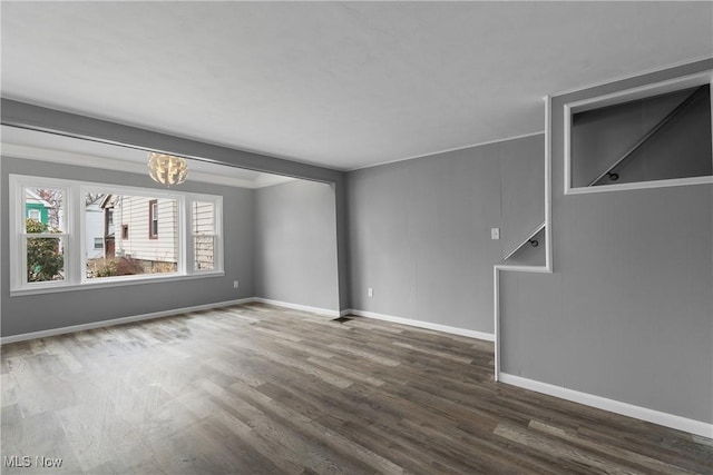 spare room with baseboards, a chandelier, and wood finished floors