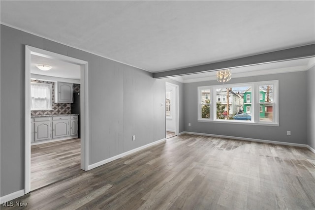 unfurnished living room with a healthy amount of sunlight, baseboards, and wood finished floors