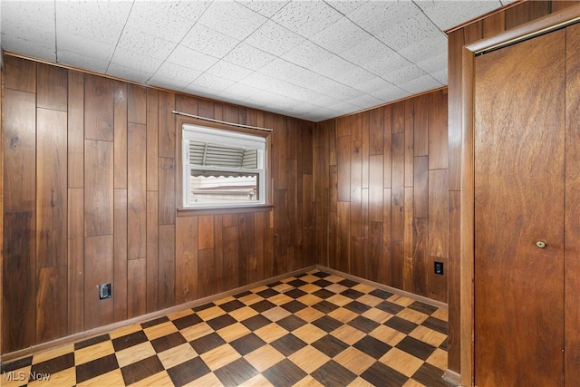 empty room featuring wood walls and baseboards