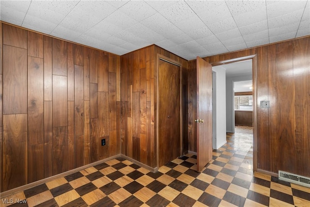 interior space featuring baseboards, wood walls, visible vents, and tile patterned floors