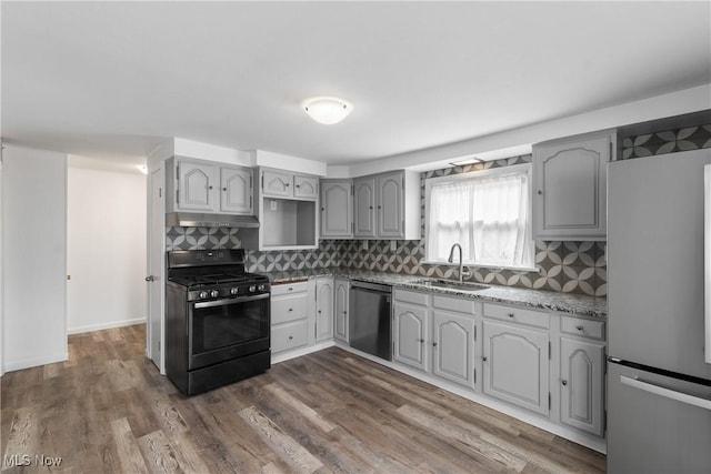 kitchen featuring under cabinet range hood, gray cabinetry, a sink, appliances with stainless steel finishes, and dark wood-style floors