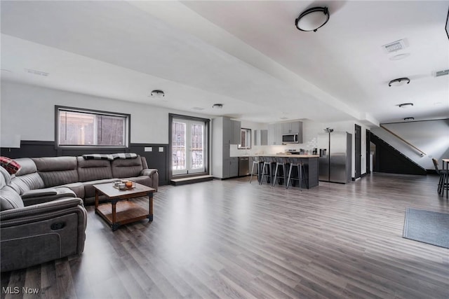 living area featuring a wainscoted wall, dark wood-style flooring, and visible vents