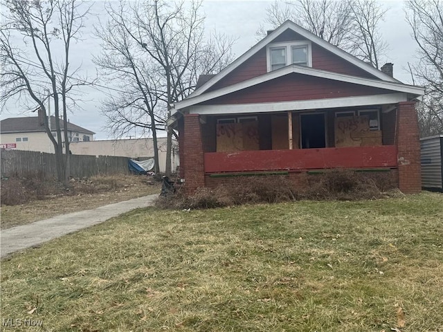 bungalow featuring brick siding, a porch, a front yard, and fence