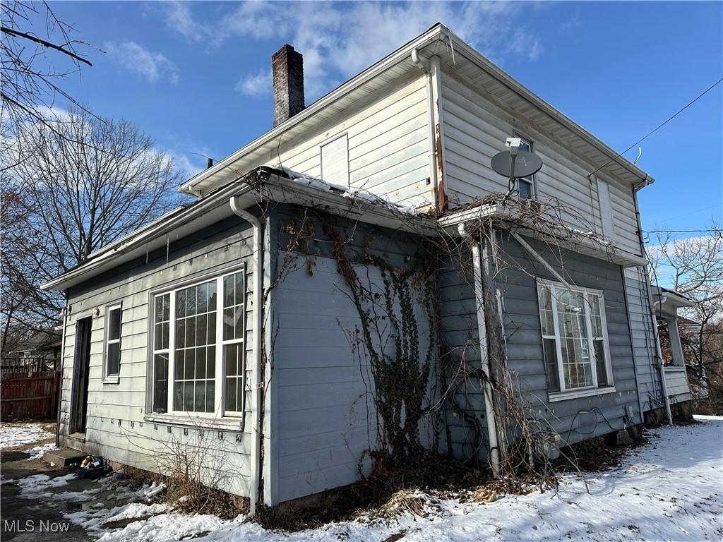 snow covered property featuring fence and a chimney