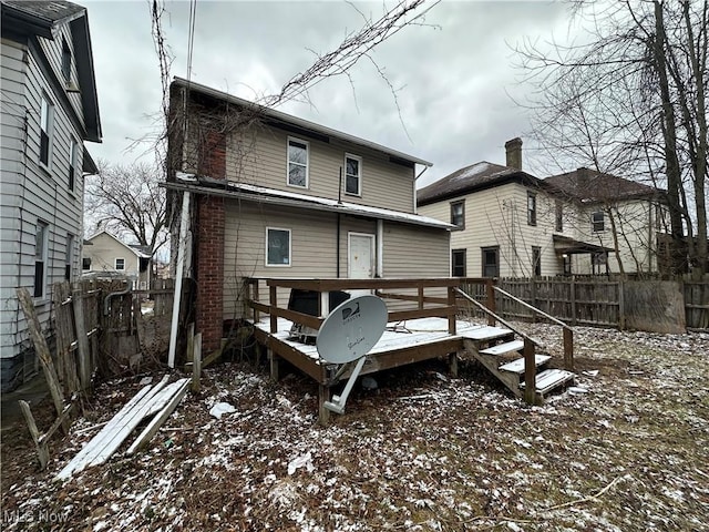 snow covered house featuring fence and a wooden deck