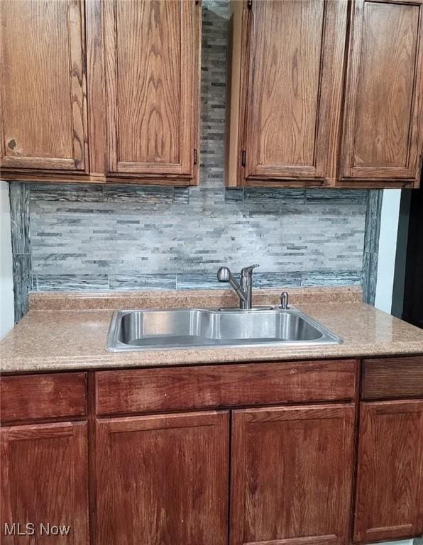 kitchen featuring decorative backsplash, light countertops, and a sink