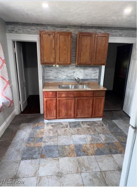 kitchen with light countertops, brown cabinets, a sink, and decorative backsplash