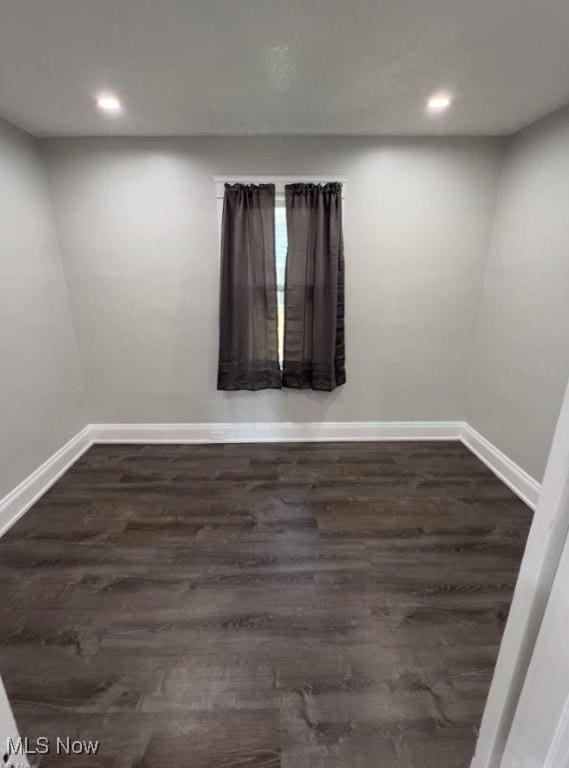 spare room with baseboards, dark wood-style flooring, and recessed lighting