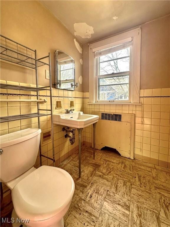 half bath featuring a wainscoted wall, toilet, tile walls, and radiator heating unit