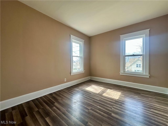 empty room featuring dark wood finished floors and baseboards