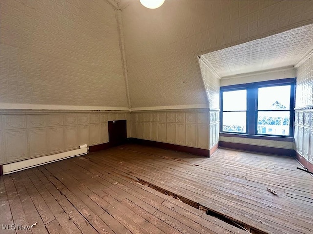 bonus room featuring wallpapered walls, a baseboard radiator, baseboards, and wood-type flooring