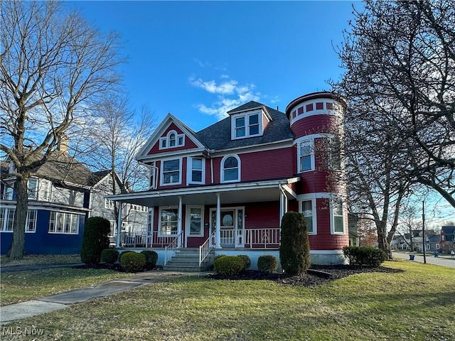 view of front facade featuring covered porch, a front lawn, and roof with shingles