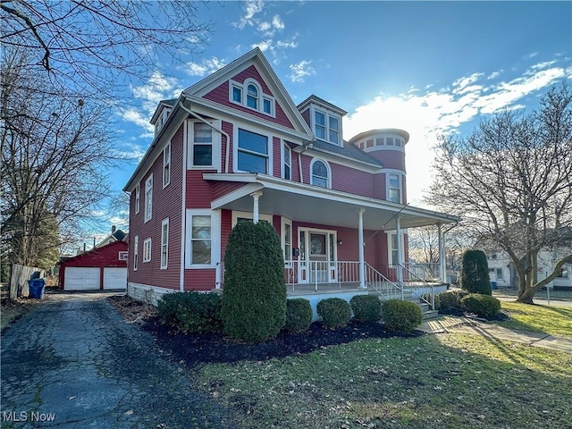 victorian home featuring an outbuilding, a porch, a front lawn, and a garage