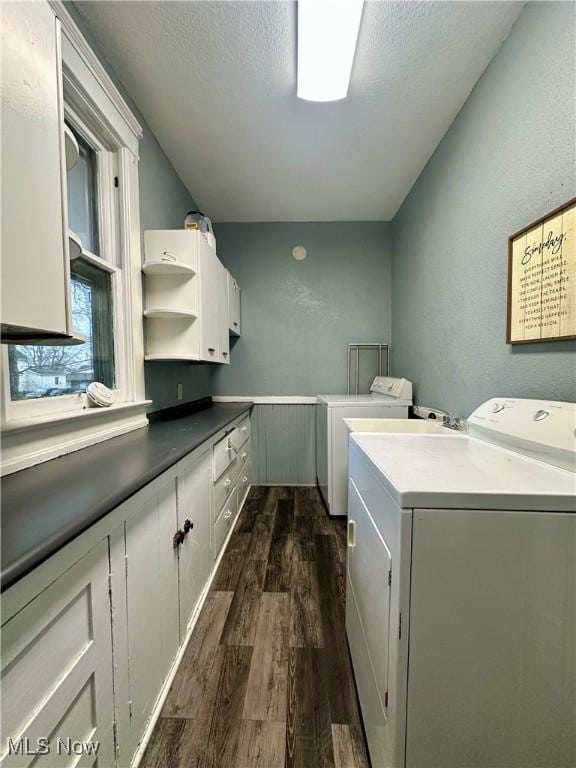 laundry room featuring cabinet space, a textured ceiling, washer and clothes dryer, and dark wood-type flooring