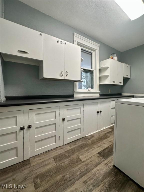 kitchen featuring dark wood-style floors, open shelves, dark countertops, white cabinets, and a textured ceiling