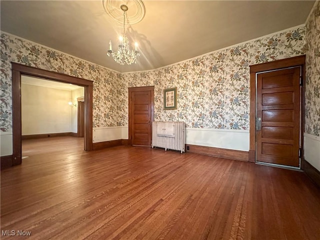 interior space with a wainscoted wall, dark wood-style flooring, and wallpapered walls