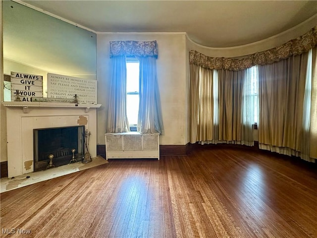 unfurnished living room featuring ornamental molding, baseboards, a fireplace with flush hearth, and hardwood / wood-style flooring