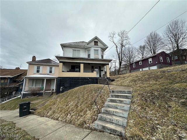 view of front of house with a porch, brick siding, and fence