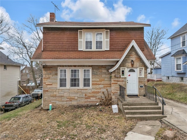 view of front of home with stone siding and a chimney