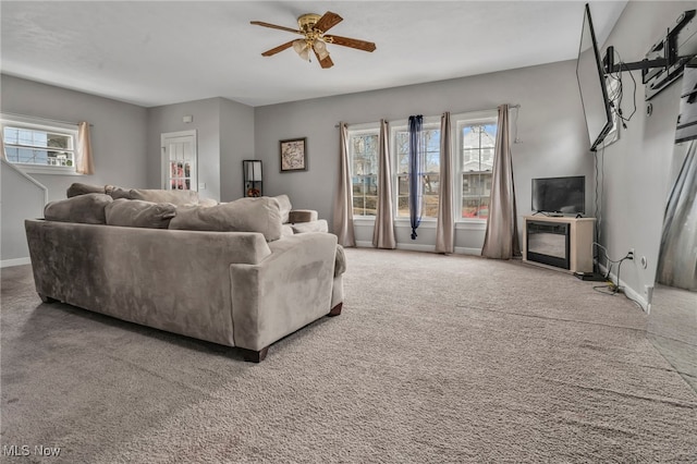 carpeted living area featuring ceiling fan and baseboards