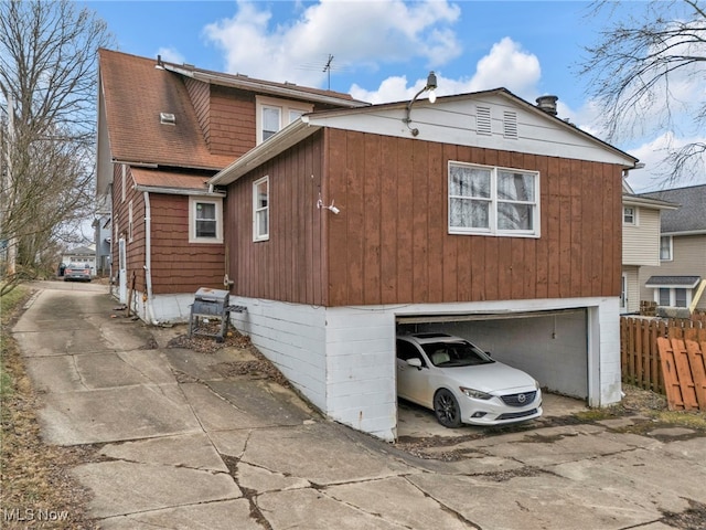 exterior space featuring a garage, fence, and concrete driveway