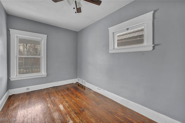 unfurnished room featuring plenty of natural light, visible vents, baseboards, and wood-type flooring